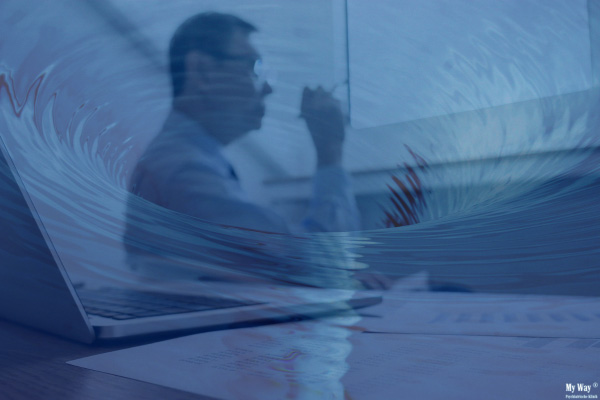 Unscharfes Bild eines Chefs am Schreibtisch sitzend, der von einem Strudel aus blauem Wasser überlagert wird, um den Burnout bei Führungskräften zu versinnbildlichen