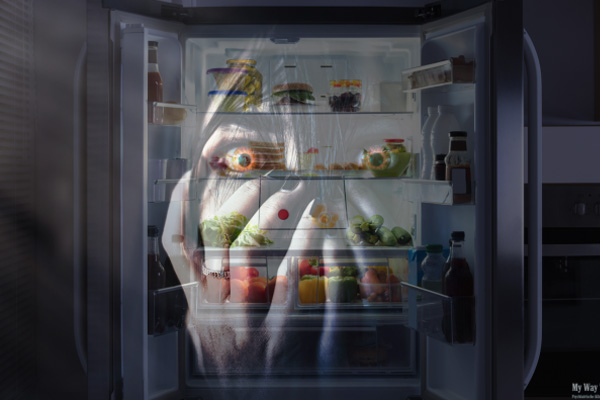 Eine erschreckte Horrorfratze blickt aus dem geöffneten Kühlschrank heraus, in dem sich gesunde Lebensmittel befinden