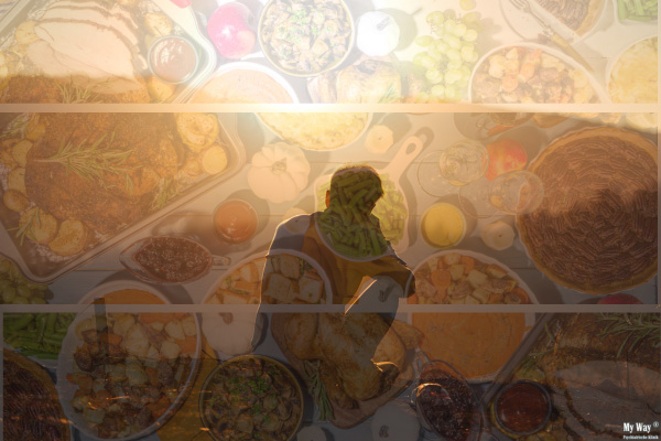 Große Auswahl verschiedener Speisen auf einem Tisch, darüber eine niedergeschlagene Person als Symbolbild für emotionales Essen und den Zusammenhang zwischen Ernährung und Depression