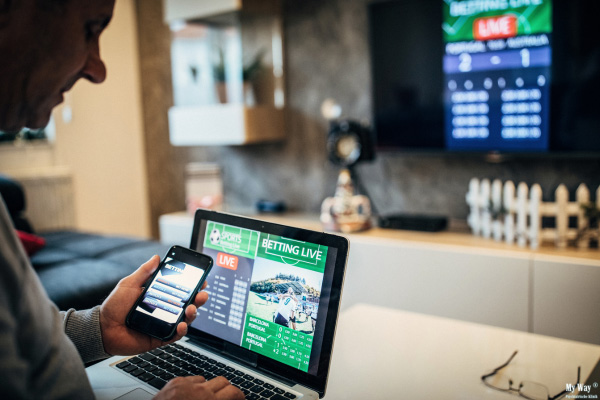 Mann nutzt elektronische Geräte für Sportwetten