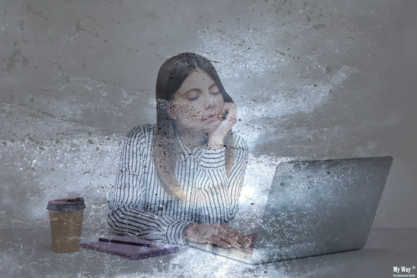 Eine Frau sitzt vor einem vereisten Hintergrund kraftlos am Laptop