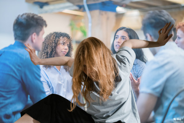 Eine Frau hat eine soziale Phobie und wehrt mit Händen und Füßen gegen eine sie umgebende Gruppe
